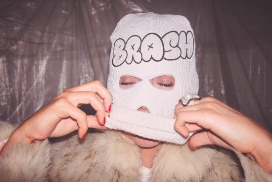 Person in ski mask with bold text design, fur coat, stylish ring, ideal for graphic design asset showcasing mockups and edgy fashion templates.